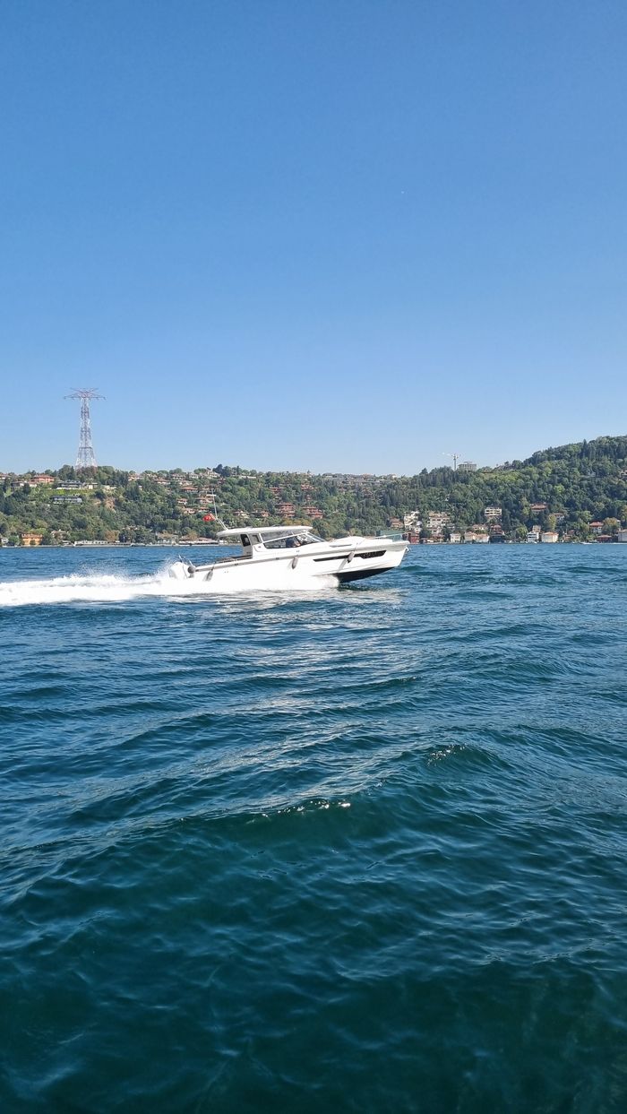 A sleek yacht travels swiftly across the vibrant blue sea on a sunny day.